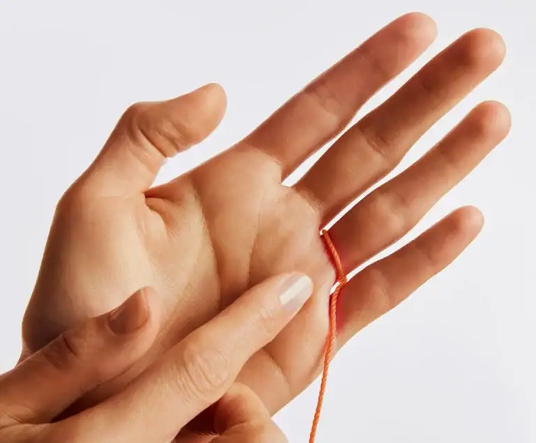 A fingertip marking the point where the string meets around the base of the finger